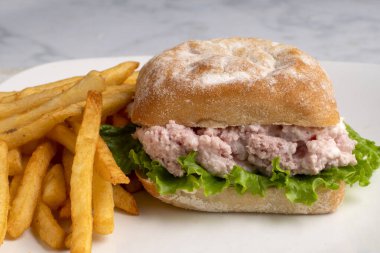 Ciabatta ekmeğine konserve jambon salatası ve marul, yanında da patates kızartması.