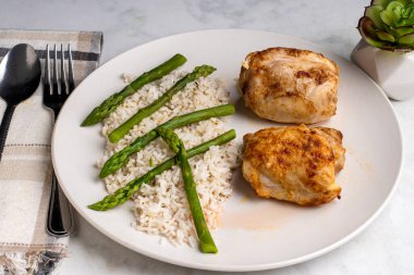  Beyaz pirinç ve kuşkonmazla servis edilen tavuk butları..