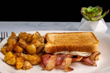 Kızarmış yumurta ve pastırmalı peynirli sandviç. Yanında da patates kızartması..