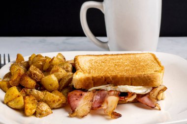 Kızarmış yumurta ve pastırmalı peynirli sandviç. Yanında da patates kızartması..