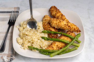 Baharatlı patates püresi ve kuşkonmazla servis edilen tavuk kanatları.