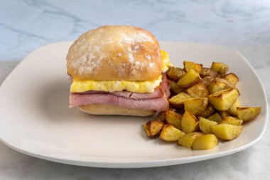  jambon ve çırpılmış yumurtalı sandviç, yanında patates kızartması.