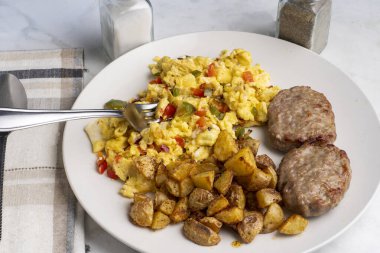 Sosisli börek ve patates kızartmasıyla servis edilen soğanlı omlet ve biber.