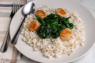 Tavada pilav, istiridye ve ıspanakla servis edilir. 