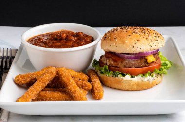 Hindili burger üstü ketçaplı, hardallı ve soğanlı acılı ve tavuk kızartmalı.