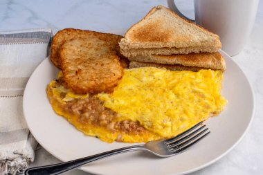 Kızarmış patates ve kızarmış ekmekle servis edilen mısır biftekli omlet.