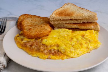 Kızarmış patates ve kızarmış ekmekle servis edilen mısır biftekli omlet.