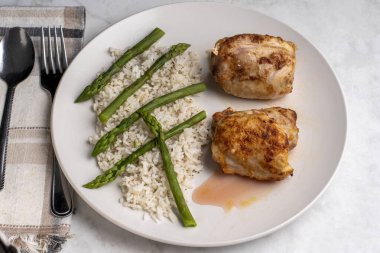  Beyaz pirinç ve kuşkonmazla servis edilen tavuk butları..