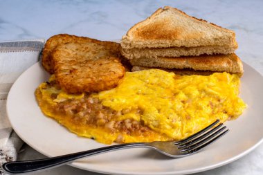 Kızarmış patates ve kızarmış ekmekle servis edilen mısır biftekli omlet.