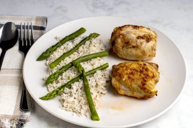  Beyaz pirinç ve kuşkonmazla servis edilen tavuk butları..