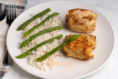  Beyaz pirinç ve kuşkonmazla servis edilen tavuk butları..