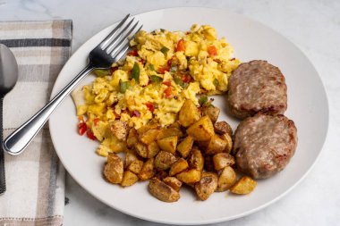 Sosisli börek ve patates kızartmasıyla servis edilen soğanlı omlet ve biber.
