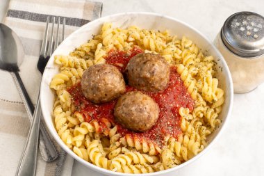 Parmesan peynirli rotini üstü ve köfte ve sosla servis edilen otlar..