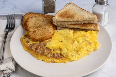 Kızarmış patates ve kızarmış ekmekle servis edilen mısır biftekli omlet.