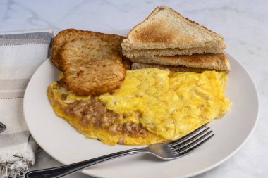 Kızarmış patates ve kızarmış ekmekle servis edilen mısır biftekli omlet.