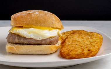 Sosis, kızarmış yumurta ve peynirli ciabbatta ekmeği ve kızarmış patates.