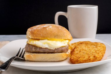 Sosis, kızarmış yumurta ve peynirli ciabbatta ekmeği ve kızarmış patates.