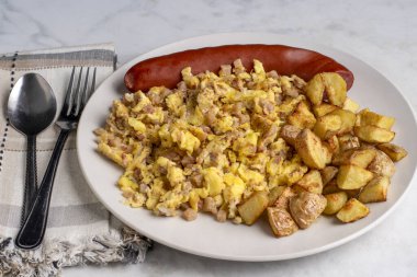 Kızarmış sosis ve ev kızartması ile servis edilen mısır bifteği ile karıştırılmış yumurta.