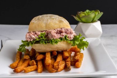 Ciabatta ekmeğinde marullu jambon salatası ve patates kızartması.