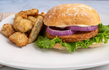 Sebzeli patates ve sebzeli patates ile servis edilen ciabatta üzerine marul ve soğanlı sebzeli burger.