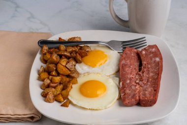 Duman sosisi ve kızarmış patates ile servis edilmiş sahanda yumurta.