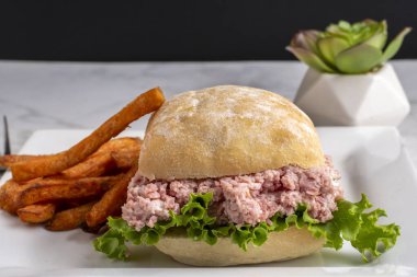 Ciabatta ekmeğinde marullu jambon salatası ve patates kızartması.