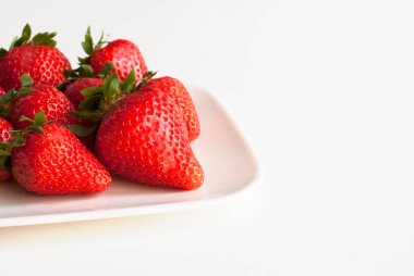 Red fresh strawberrieson the white plate isolated on white background