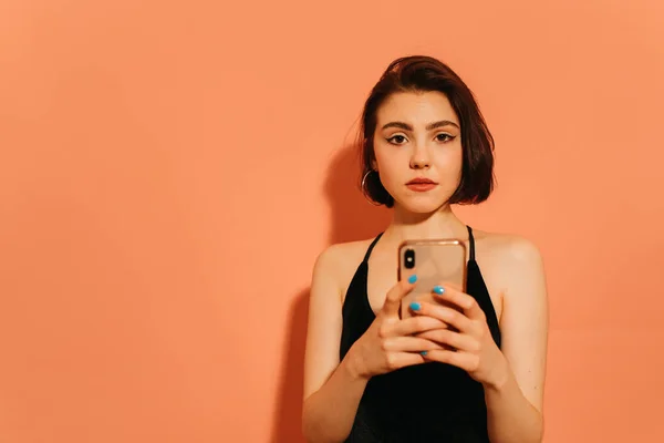 Young Adult Woman Holding Smartphone Hands Tensely Looking Camera Orange — Stock Photo, Image