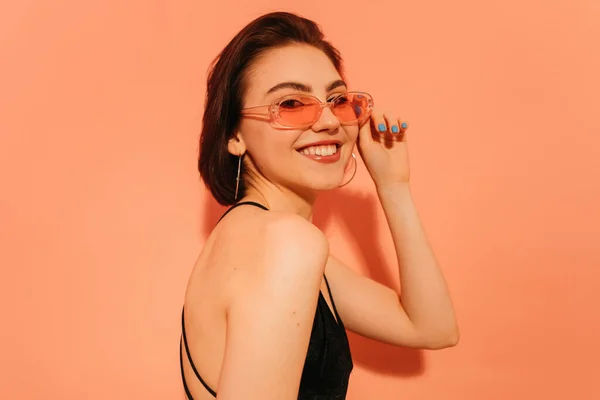 Smiling Young Woman Posing Looking Camera Adjusting Sunglasses Orange Background — Stock Photo, Image