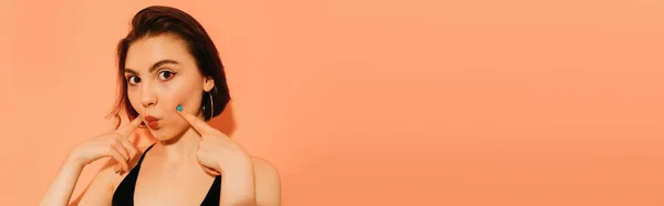 Young Woman Grimacing Pouting Lips Hands Face Orange Background Banner — Stock Photo, Image