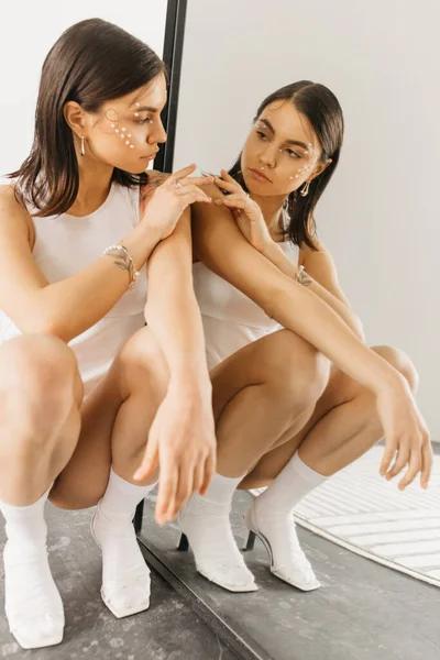 Jonge Stijlvolle Vrouw Met Decoratieve Make Zitten Squat Pose Buurt — Stockfoto