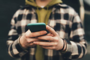 Açık havada bulanık bir adamın ellerinde akıllı telefon görüntüsü. 