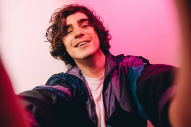 Mutlu kıvırcık adam pembe arka planda kameraya bakıyor. 