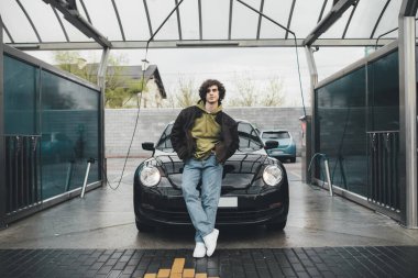 Otomobilin yanındaki kot pantolonun cebinde el ele tutuşan adam oto yıkama servisinde. 