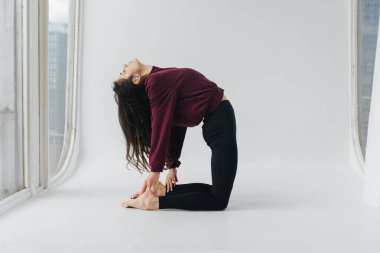 Beyaz zeminde deve yogası yapan Ermeni güzel bir kadının yan görünüşü