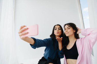 Genç Ermeni kadın, arkadaşıyla akıllı telefondan selfie çekerken hava öpücüğü gönderiyor.