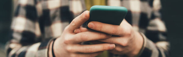 Cropped view of blurred man using smartphone, banner 