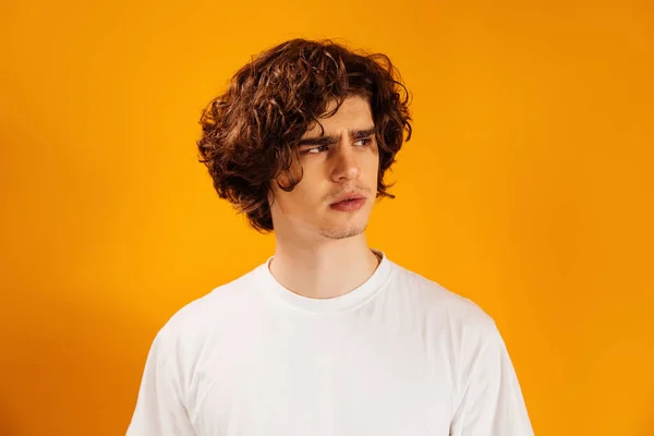 Beyaz tişörtlü adam turuncuya tek başına bakıyor. 