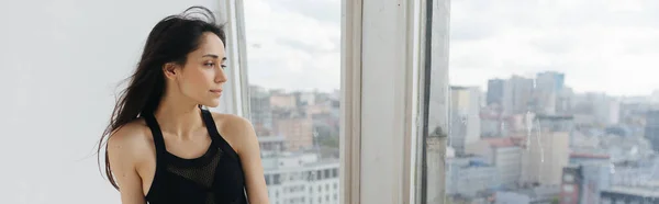 Siyah bluzlu genç Ermeni kadın evdeki pencerenin yanında rüya görüyor, afiş