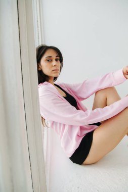 Beyaz gömlekli ve siyah mini etekli genç Ermeni kadın yerde oturmuş kameraya bakıyor.