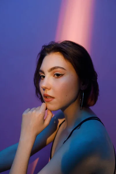Porträt einer nachdenklichen jungen Frau auf violett und rosa Hintergrund — Stockfoto