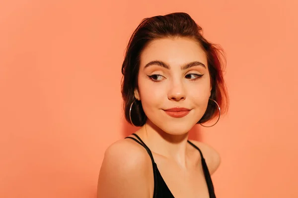 Shy young woman with cat eyes makeup on orange background — Stock Photo