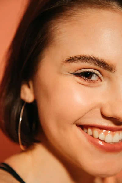 Nahaufnahme eines lächelnden jungen Frauengesichts mit Sommerschminke und Katzenaugen in Orange — Stockfoto