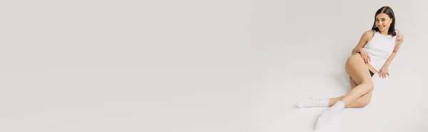 Sensuale giovane donna in top bianco, calze e mutandine nere sdraiato su sfondo grigio, banner — Foto stock