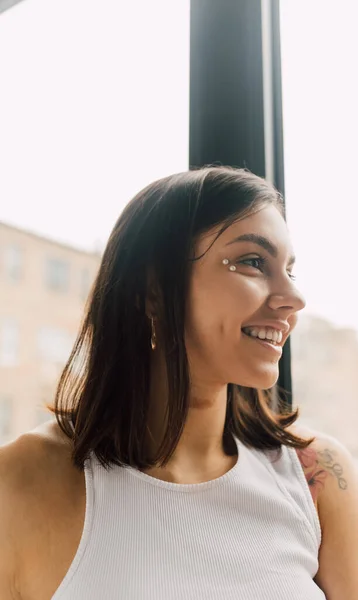 Portrait of young smiling woman with decorative elements in makeup standing on blurred background — Stock Photo