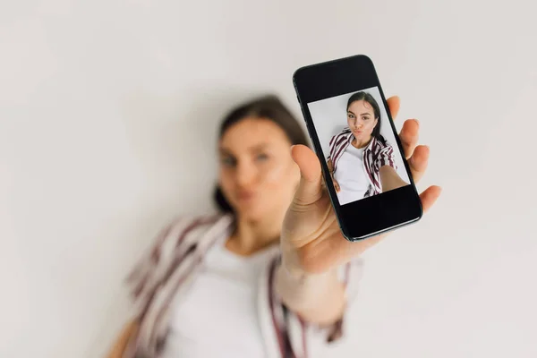 Smartphone con foto selfie de mujer joven con mueca de cara de pato sobre fondo borroso - foto de stock
