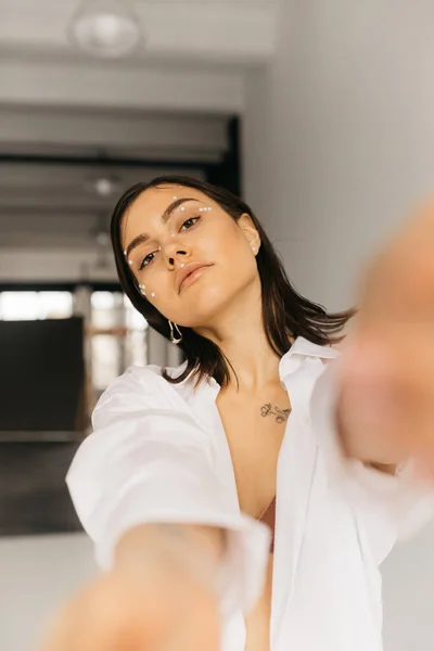 Mujer joven con las manos extendidas mirando a la cámara sobre fondo borroso - foto de stock