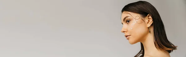 Side view shot of young woman with decorative makeup and beads on face isolated on grey, banner — Stock Photo