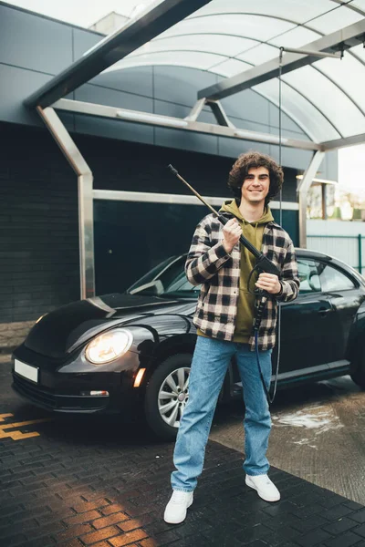 Uomo sorridente con rondella di pressione in piedi vicino auto all'aperto — Foto stock