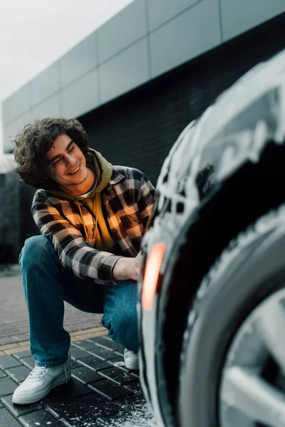 Fröhliche Fahrerin nahe verschwommenem Auto in Schaumstoff — Stockfoto